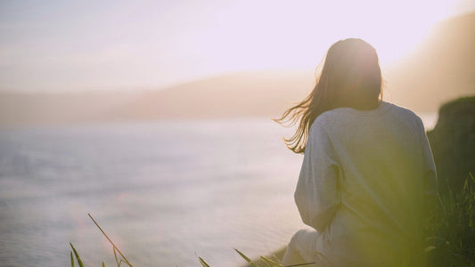 Frau sitzt am Meer und genießt die Ruhe - Beitragsbild Slow Living